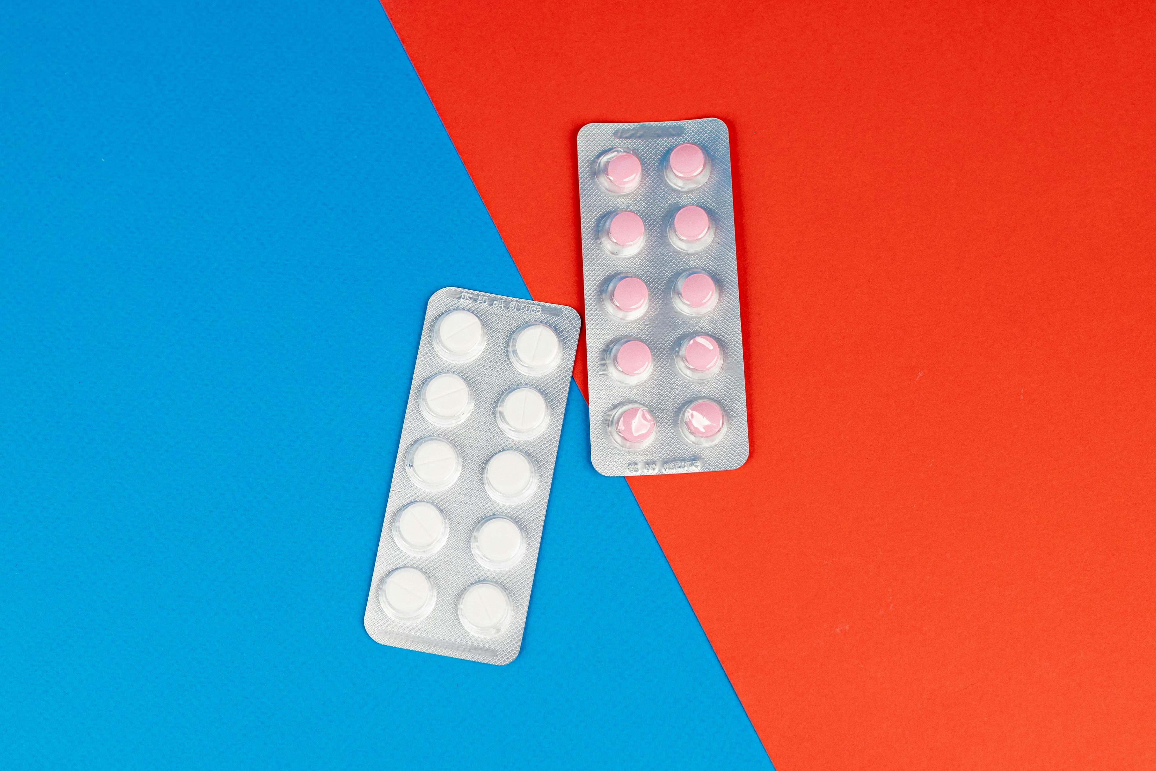 Flat lay of pill blister packs on a red and blue surface, ideal for healthcare themes.